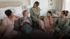 Diverse bridesmaids relaxing naturally in coordinated pajama sets in a bright wedding suite
