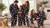 Multigenerational family wearing matching personalized pajama sets in a bright living room