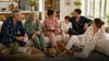 Family and friends naturally wearing coordinated personalized-style pajamas in a bright home