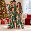 Family of four in matching green Christmas dog satin long pajama sets in a decorated Christmas living room