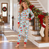 Woman in the snug aqua cocoa mug and cookie Christmas pajama set standing on a garland-decorated staircase