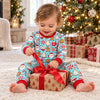 Baby in the baby-size aqua cocoa mug and cookie Christmas pajama set opening a gift by the tree