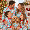 Close-up of a family hugging their dog in matching aqua cocoa mug and cookie Christmas pajamas and bandana